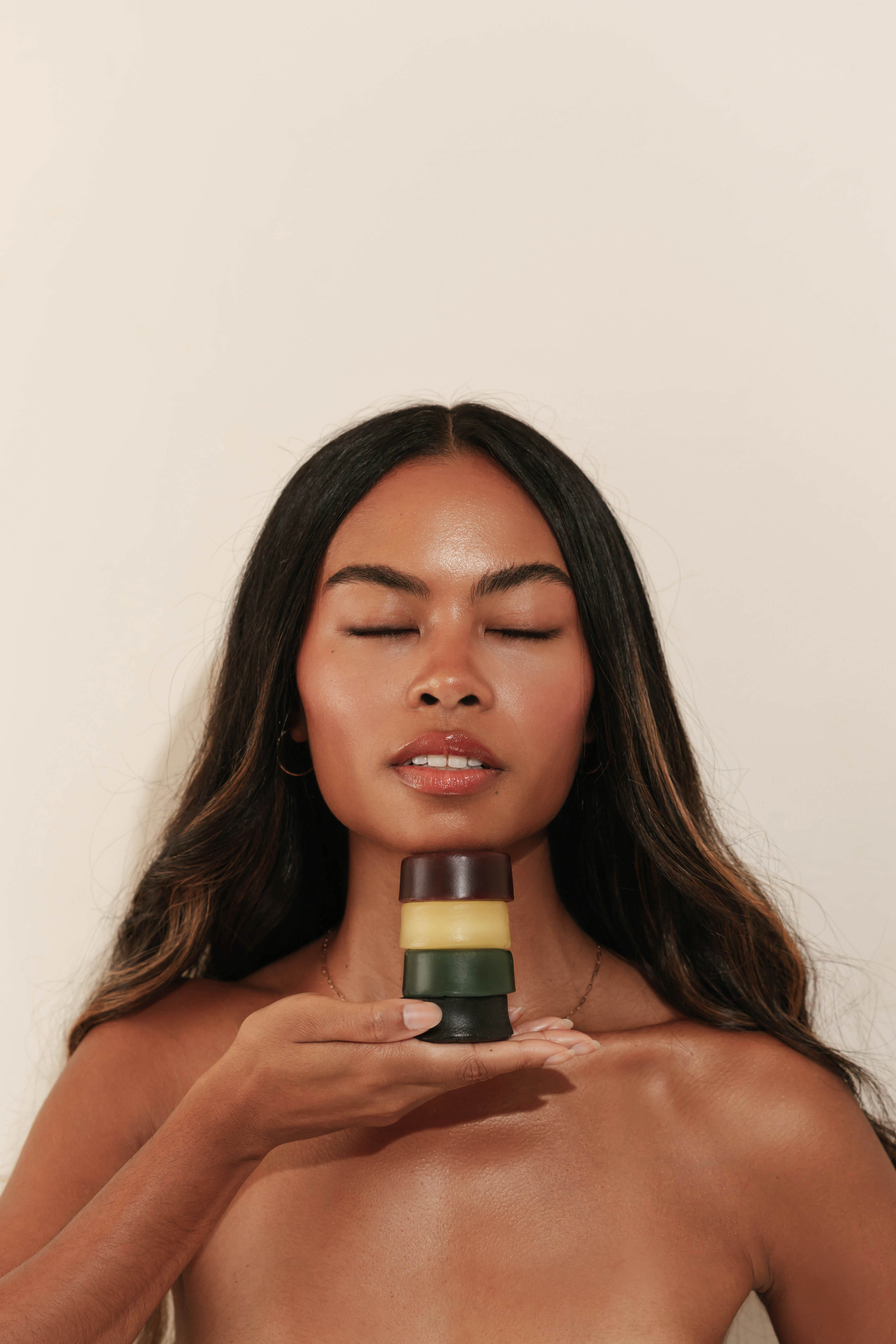 Woman holding four hair care bars against a plain background
